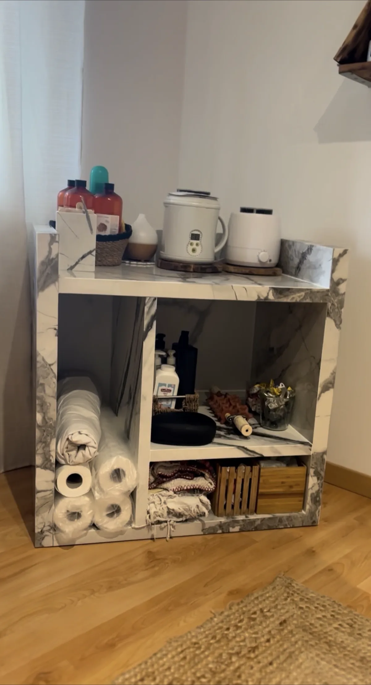 Meuble de rangement entièrement habillé de carrelage effet marbre veiné blanc et gris, façonnage sur toutes les faces.